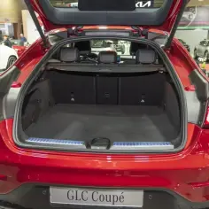 Czerwony Mercedes GLC Coupe z otwartym bagażnikiem. Wnętrze jest puste, gotowe na bagaże. Sprawdź mercedes glc wymiary, by zaplanować podróż.
