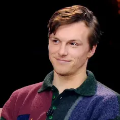Uśmiechnięty Tomasz Włosok, gwiazda filmów, w kolorowym swetrze.