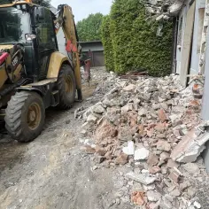 Koparka przy gruzowisku. Rozbiórka budynku, szacowanie burzenie ścian cena.