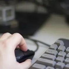 Dłoń trzyma myszkę, klawiatura obok. Czas na przeglądanie internetu w trybie incognito, by zachować prywatność.