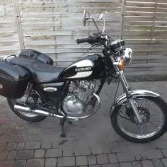 Czarny motocykl Suzuki GN125 z kuframi, gotowy na podróż.