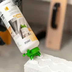Ręce w rękawicach aplikują klej Ytong EasyFix na bloczek. Czy klejem do płytek można murować? Ten klej jest do bloczków Ytong.