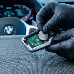 Rękawiczki ochronne ułatwiają wymianę baterii w kluczyku BMW. Widać deskę rozdzielczą i kierownicę.