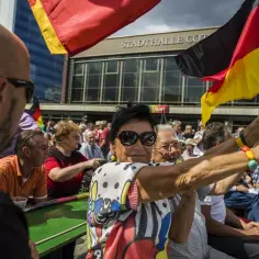 Ludzie z flagami Niemiec, państwa graniczące z Niemcami, świętują przed Stadthalle Cottbus.