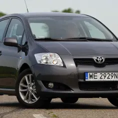 Szary Toyota Auris 2012 na drodze, z widocznym kierowcą.