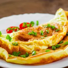Puszysty omlet z zieloną cebulką i pomidorkami. Idealny przepis na omlet na szybkie śniadanie.