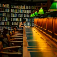 Dziewczyna uczy się w bibliotece, otoczona regałami pełnymi książek. To miejsce, gdzie często spędzają czas uczniowie, przygotowując się do lekcji i sprawdzianów.