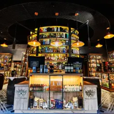 Wnętrze Domu Whisky w Jastrzębiej Górze. Bogate menu alkoholi, półki uginające się od butelek, beczki i stylowe oświetlenie.