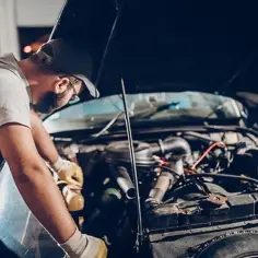 Mechanik w rękawiczkach bada silnik, próbując zdiagnozować nierówną pracę silnika.