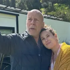 Emma Heming Willis wspiera Bruce'a Willisa w walce z chorobą. Para w czułym uścisku na tle zieleni.