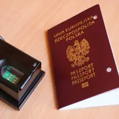 Skaner linii papilarnych obok polskiego paszportu. Odciski palców do paszportu to zabezpieczenie tożsamości.