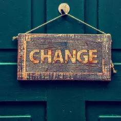 Drewniana tabliczka z napisem "CHANGE" wisi na zielonych drzwiach. Symbolizuje to zmianę imienia w Polsce, która może być początkiem nowego rozdziału.