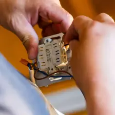 Ręce montują mechanizm gniazdka. Sprawdzanie punktu elektrycznego przed zakupem, by poznać jego cenę.