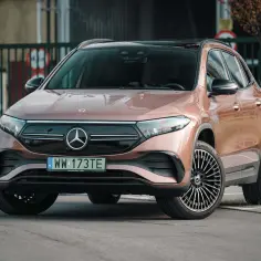 Elegancki, brązowy Mercedes EQA z czarnym dachem i stylowymi felgami stoi na parkingu.