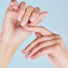 Dłonie z naturalnymi paznokciami, jedna dotyka drugiej. Zastanawiasz się nad manicure japoński wady?