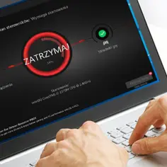 Użytkownik korzysta z laptopa z programem Driver Booster, który jest **programem do aktualizacji sterowników**. Widoczny jest postęp skanowania.