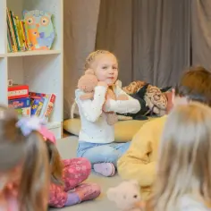 Dzieci siedzą na podłodze, słuchając bajki. To idealny moment, kiedy dziecko może iść do przedszkola.