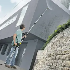 Mężczyzna myje elewację domu myjką Karcher z teleskopową lancą. Idealny wybór, jaki Karcher do mycia elewacji.
