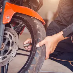 Mechanik sprawdza ciśnienie w oponie motocykla. Dowiedz się, jaka jest wymiana opon w motocyklu cena.