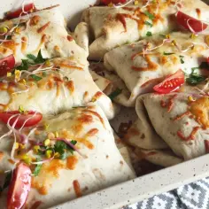 Tortilla z mięsem mielonym i serem, zapieczona z pomidorkami i kiełkami. Pyszne danie na obiad.