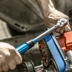 Mechanik używa klucza dynamometrycznego do świec, precyzyjnie dokręcając element silnika.