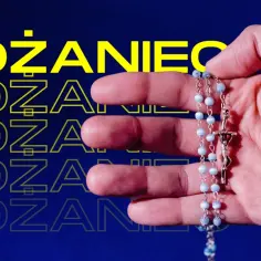 Dłoń trzymająca różaniec z niebieskimi paciorkami i krzyżem.