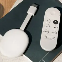 Biały Chromecast z pilotem do Google TV. Ułatwia dostęp do ulubionych aplikacji, takich jak YouTube i Netflix.