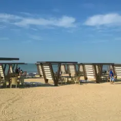 Plaża z zacienionymi stolikami i krzesłami. W tle widać wodę, która może być Morzem Kaspijskim, ale czy morze kaspijskie to jezioro?