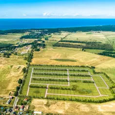 Działki budowlane nad morzem, z widokiem na błękitną wodę i zielone pola. Idealne miejsce na wymarzony dom.