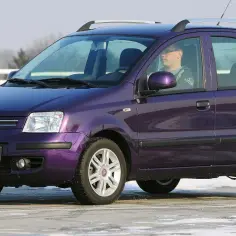 Fioletowy Fiat Panda, idealny jako jedno z aut do 15 tys. zł, z kierowcą za kierownicą.