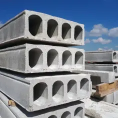 Stos betonowych płyt stropowych kanałowych pod błękitnym niebem. Gotowe do budowy domu.
