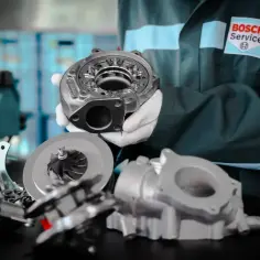 Mechanik w rękawiczkach prezentuje turbosprężarkę. Czy diesel lubi wysokie obroty? To pytanie dotyczy wydajności silnika.
