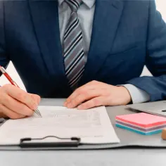 Biznesmen podpisuje dokumenty. Czy delegacja a praca zdalna z zagranicy to nadal podróż służbowa?