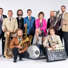 Zespół muzyczny gotowy do zagrania fanfary. W rękach instrumenty dęte, klawisze i perkusja.