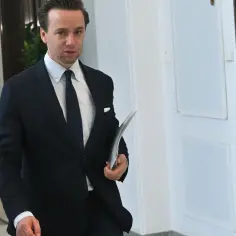 Wicemarszałek Sejmu w garniturze idzie korytarzem, trzymając teczkę.