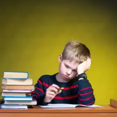Zmęczony chłopiec z książkami. Zastanawia się, ile czasu ma szkoła na zorganizowanie nauczania indywidualnego.