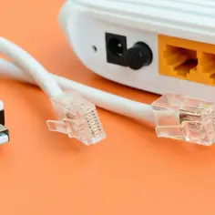 Router z kablami Ethernet i USB na pomarańczowym tle.