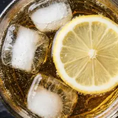 Orzeźwiający whiskey z tonikiem, z plastrem cytryny i kostkami lodu, na ciemnym tle.