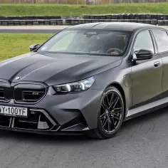 Matowy, grafitowy BMW M5 F90 na torze wyścigowym, z czarnymi felgami i agresywnym body kitem.