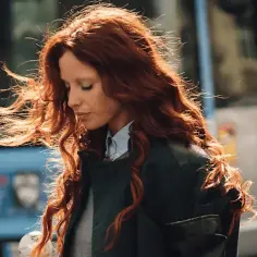 Kobieta z burzą rudych, shaggy hair, wiatr rozwiewa jej włosy.