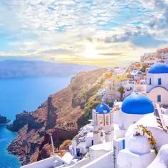 Santorini, Grecja najpiękniejsze miejsca: białe domy z niebieskimi kopułami na klifie nad lazurowym morzem.