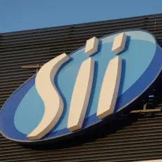 Logo "SII" na niebieskim tle z białymi elementami, na tle ciemnej fasady i nieba.