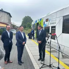Mężczyźni w garniturach stoją na peronie obok nowoczesnego pociągu Pomorze Zachodnie, który zabierze pasażerów do Mielna Koszalińskiego.