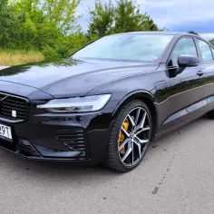 Czarny Volvo S60 V8 z żółtymi zaciskami hamulcowymi na tle zieleni.