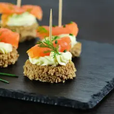 Mini kanapeczki z łososiem i kremowym serkiem, idealne na efektowną kolację dla znajomych.