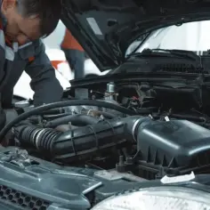Mechanik pracuje przy silniku samochodu, sprawdzając, ile kosztuje wymiana oleju.