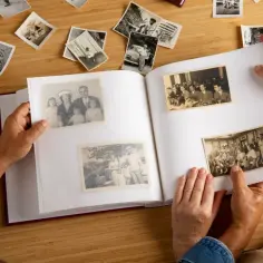 Dwie osoby przeglądają album ze starymi zdjęciami, wspominając przeszłość. Proces renowacji starych zdjęć pozwala zachować te cenne chwile.