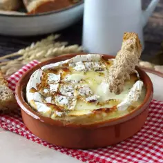 Pieczony camembert w naczyniu, z chlebem i ziołami.