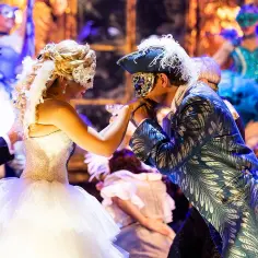 Upiór w operze: mężczyzna w maskę całuje dłoń kobiecie w balowej sukni.