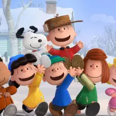 Grupa przyjaciół z Fistaszków, w tym Charlie Brown i Snoopy, cieszy się zimową zabawą na śniegu.